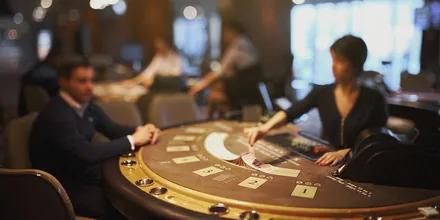 Dealer og spillere ved et blackjackbord i et casino